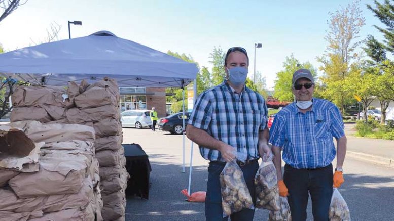 WSPC commissioners Grant Morris and Roger Hawley grab bags of potatoes to give away in Auburn, Wash.